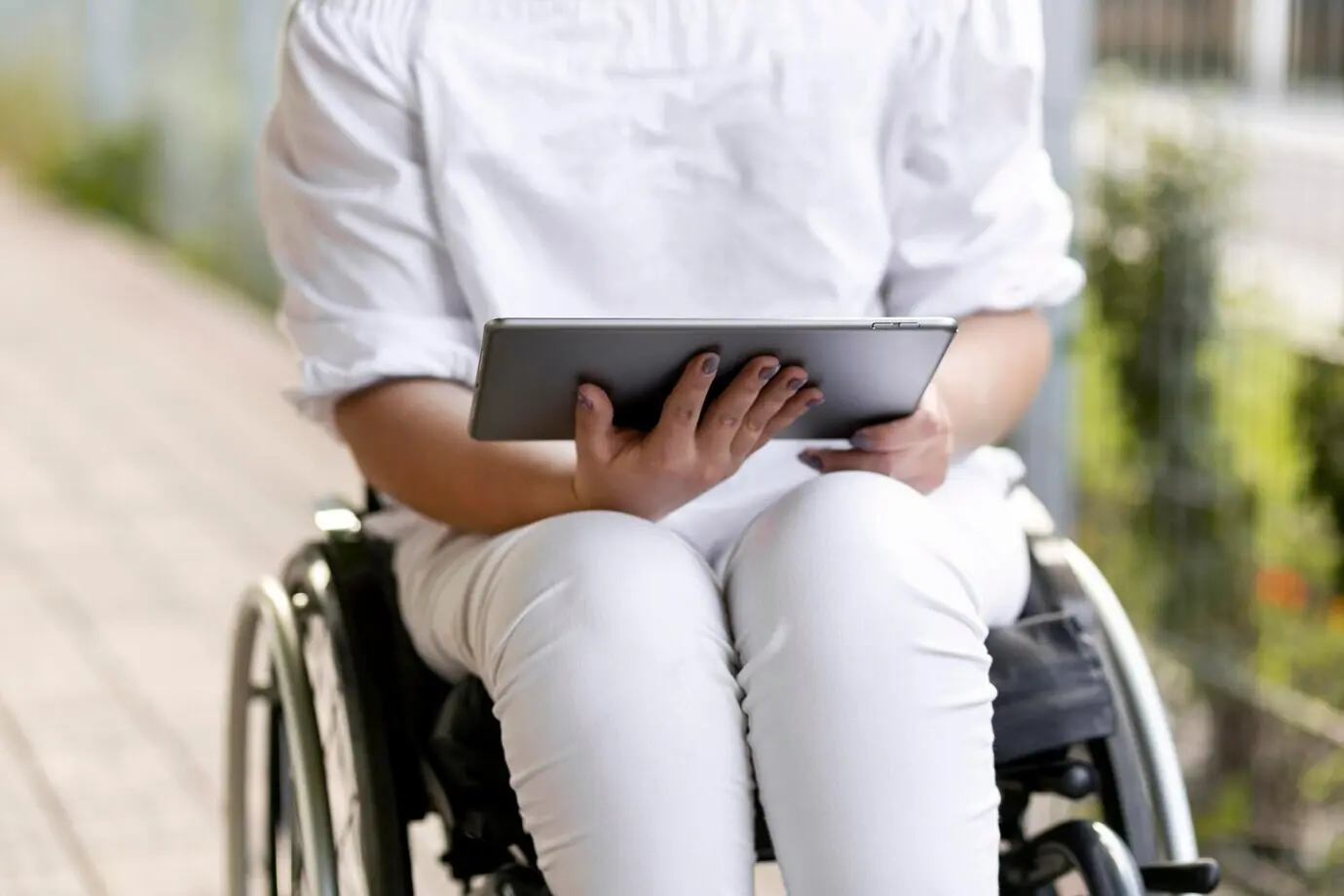 Front-facing view of a woman in a wheelchair with a tablet